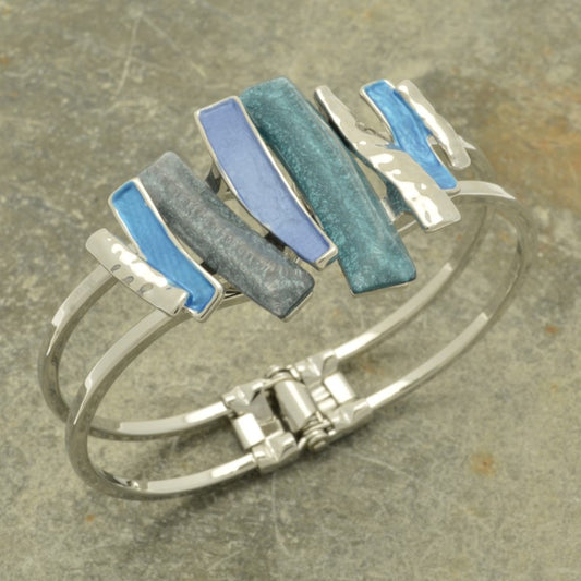 This stylish blue layered mix bracelet is the perfect addition to any outfit. Featuring a fresh touch of silver in a hinged style, this bracelet is designed to fit all sizes of wrist. The beautiful combination of blue resin and paint will be sure to turn heads!