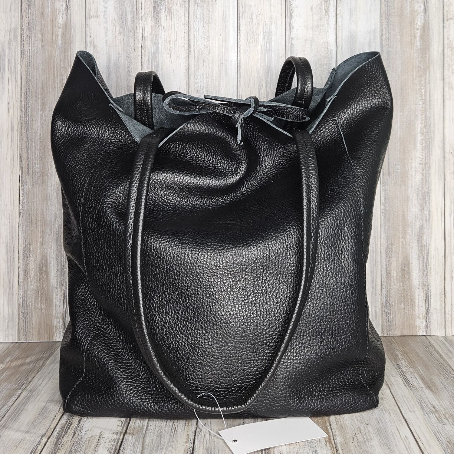 Experience luxury and organization with our pebbled leather Tote Bag! Made with soft Italian leather, this large tote features a convenient internal zip pocket and a stylish leather drawstring closure. Stay on-trend and chic with our fabulous black bag!
