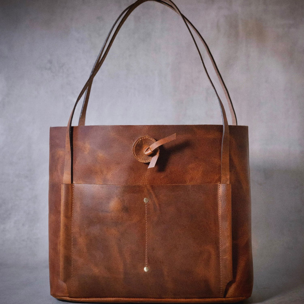 Introducing the Billy-Brown Leather Handbag, a sophisticated and exclusive tote bag crafted from luxurious buffalo leather in a unique distressed finish. With a quick access front and back sleeve, one main compartment, and an organizer panel for cards and phone, this unlined bag flawlessly blends style and functionality. Elevate your wardrobe with this elegant and tasteful bag.