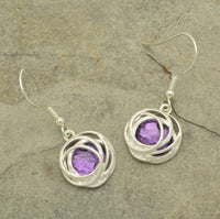 Make a bold statement with the Bright Purple and Silver Drop Earrings! These stunning earrings feature a beautiful bold purple resin backed by aluminium foil and surrounded by matt silver hooped metalwork, creating a unique and captivating blend of color and texture. Be glamorous and daring with these one-of-a-kind earrings!  These earrings are  approx 1.5cm in diameter and hang approx 2cm down from fishhooks.