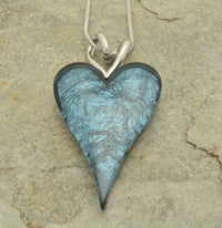 This beautiful Dark Teal Necklace is the perfect way to add subtle yet stylish sparkle to any outfit. Crafted with a lustrous foil-backed resin, the striking two-heart pendant is perfect for making a subtle statement. Wear it and dazzle!  The full pendant measures approx 2.8cm wide by 5.5cm high. The necklace measures 41cm or 16″ long and fastens with a lobster clasp and 8cm extension chain.