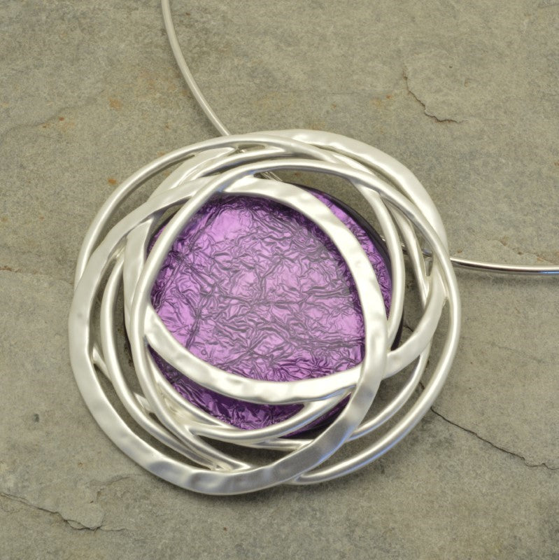 Indulge in luxury with our Purple And Silver Statement Necklace. Featuring a large resin pendant in striking purple and a delicate partial torque chain in matt silver, this necklace is the perfect statement piece for any outfit. Elevate your style with this exclusive and tasteful necklace.
