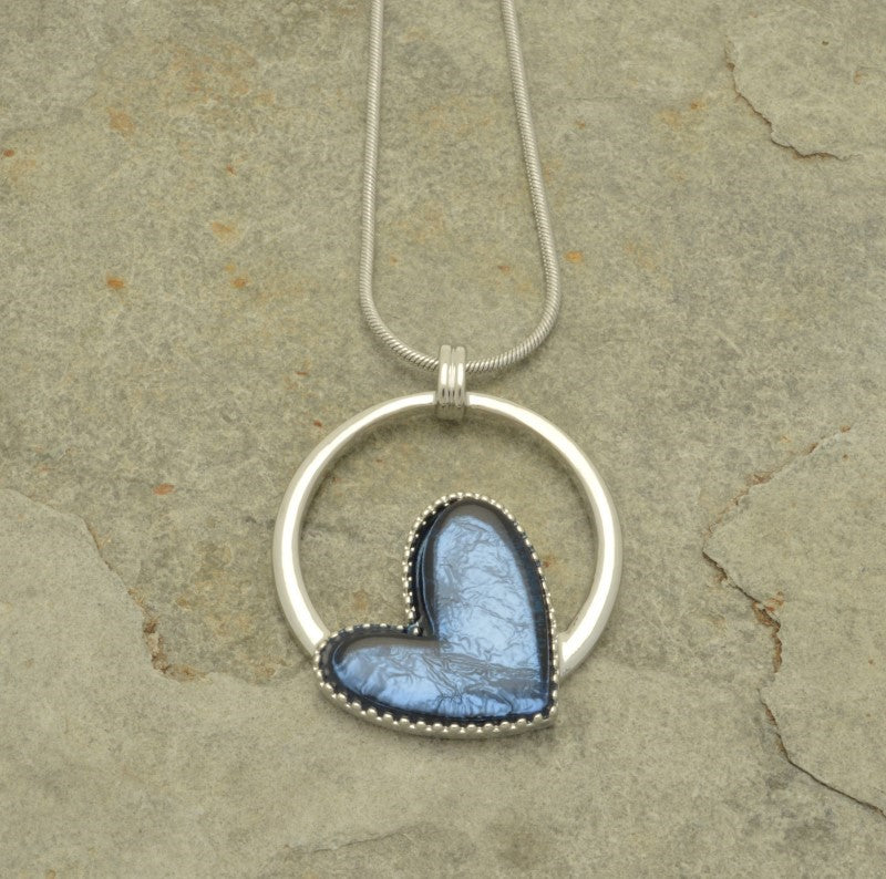 This denim blue necklace is a captivating addition to any jewellery collection. Expertly crafted with a resin heart on a silver hoop, the necklace catches light with aluminum foil backing to create texture and depth. Featuring a lobster clasp and 8 cm extension chain, it measures 41 cm in length.