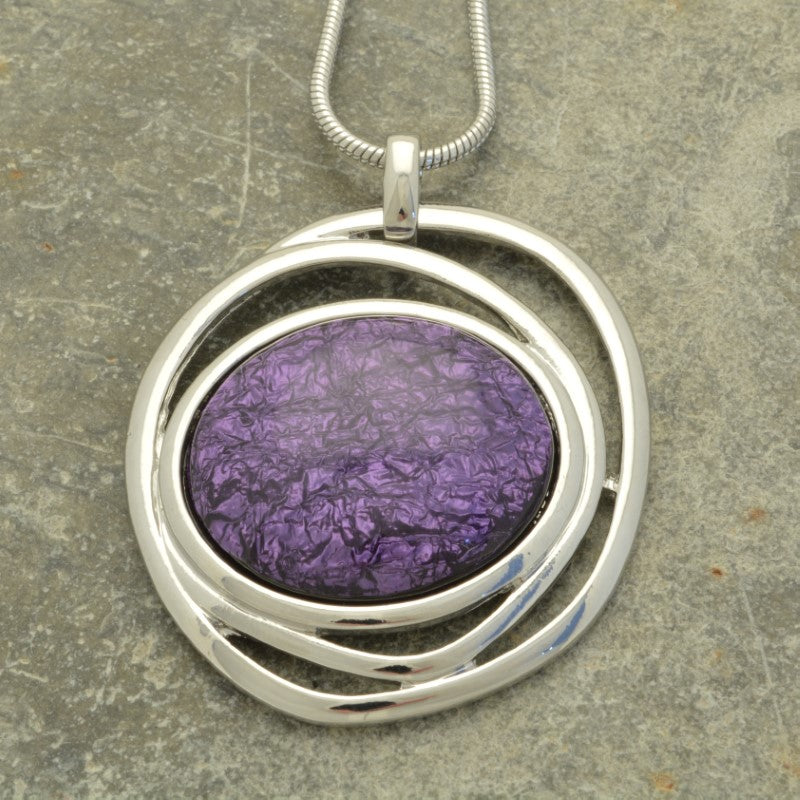 This eye-catching necklace is crafted with luxurious pinky purple resin and a swirl of shiny silver, backed with aluminium foil for added depth and texture. Its unique 5cm by 4.5cm design hangs elegantly from a 75cm snake chain with a 5cm extender for a customised fit.
