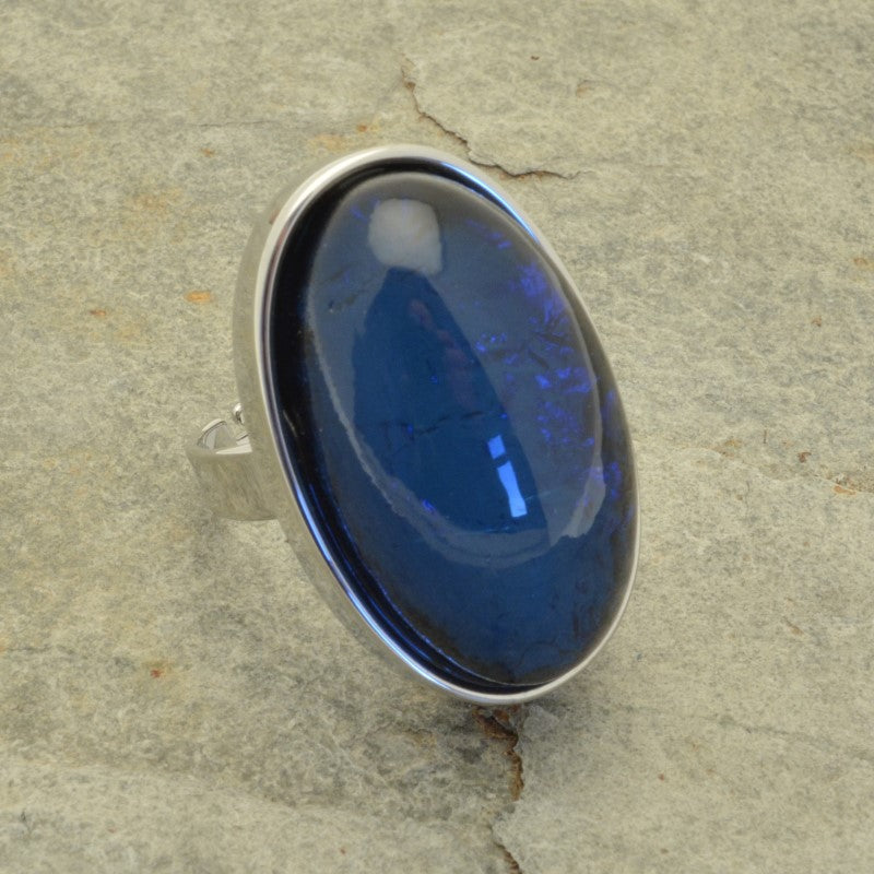 This Chunky Blue Foil Resin Adjustable Ring is the perfect addition to any jewelry collection. It boasts an eye-catching  blue color and a magnificent iridescent resin, adding an opalescent effect. Stylish and unique, it will coordinate with other Miss Milly jewellery and is adjustable for your convenience. Its dimensions are 3.3cm long by 2cm wide. Make a stylish statement with this beautiful ring!