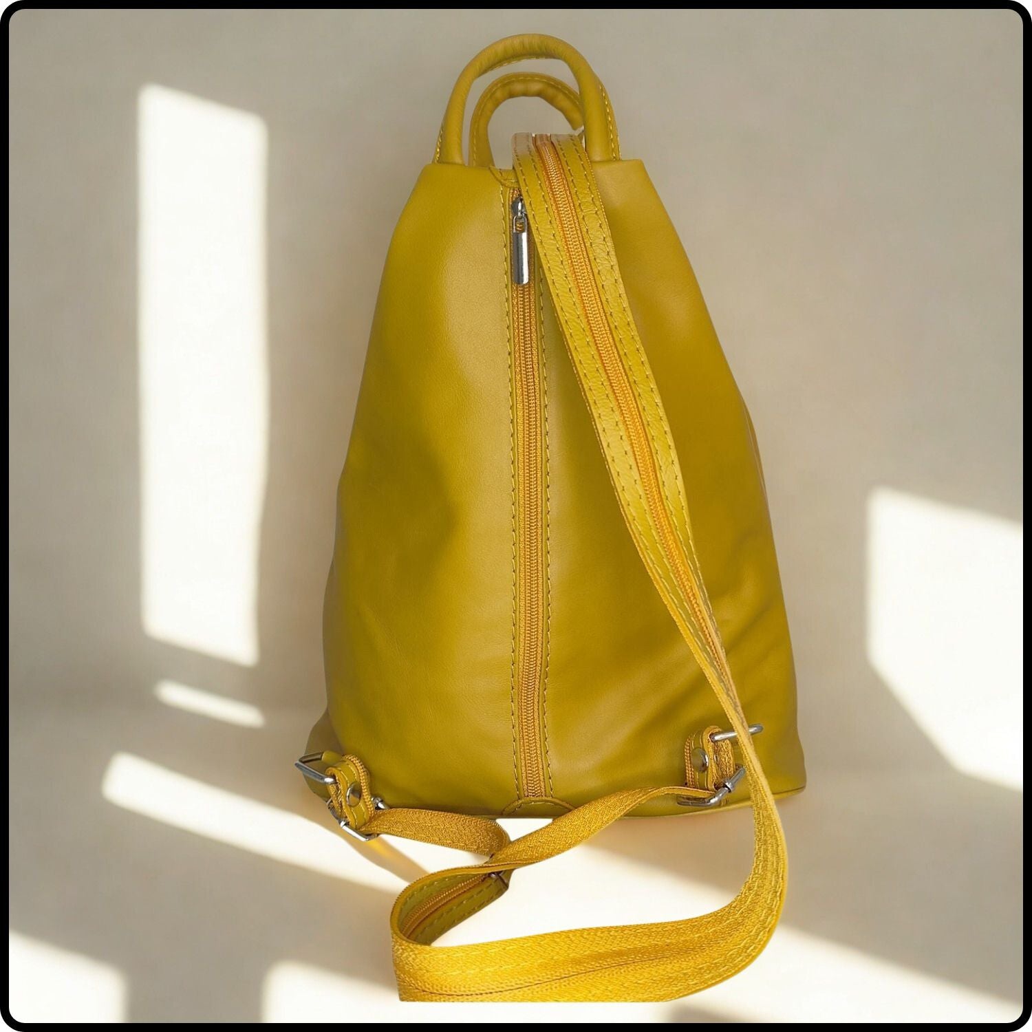 Yellow leather backpack with a strap on a light background