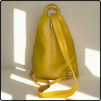 Yellow leather backpack with a strap on a light background