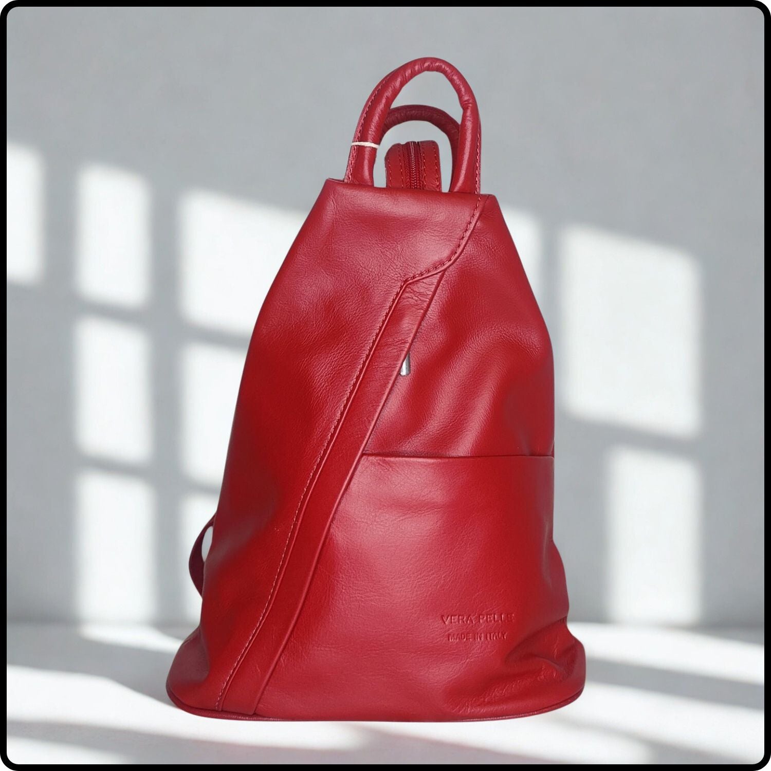 Red leather backpack on a light gray background