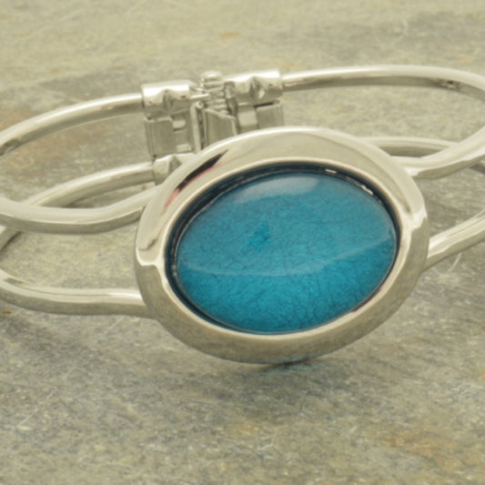 This Aqua Marble Resin Bracelet embodies a contemporary style with its unique texture and mesmerizing visual effect. This statement piece adds a touch of luxury to any outfit. Its hinged opening ensures a comfortable fit for all wrist sizes.